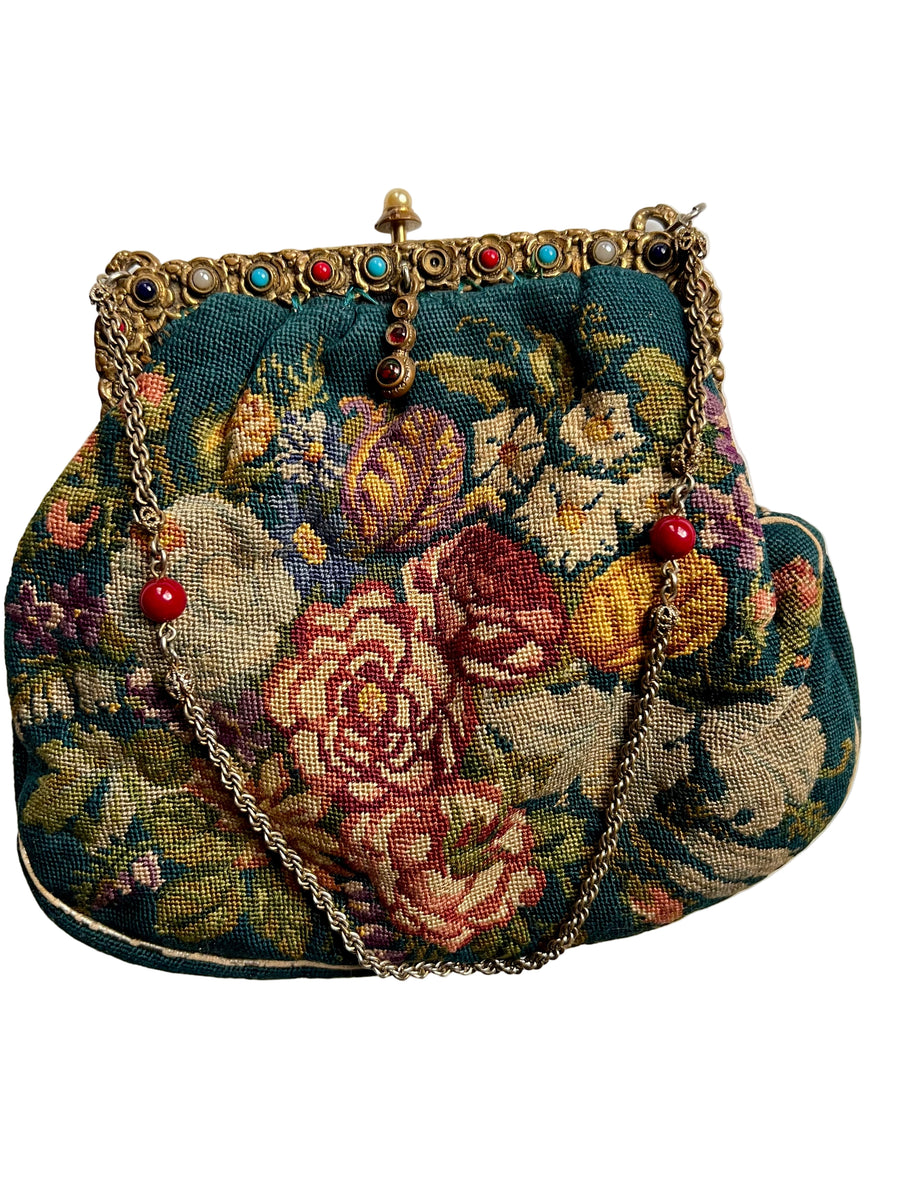 Floral embroidered handbag with decorative chain on a white background
